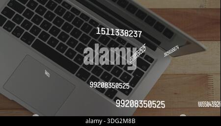 Displaying silver laptop resting partly open on wooden tabletop, showing numeric overlays, sticker Stock Photo