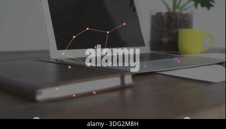 Displaying silver laptop resting on wooden desk at home office, with notebook, mug, plant, paper Stock Photo