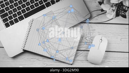 Showing notebook lying on wood desk with silver laptop white mouse, potted flowers, network overlay Stock Photo