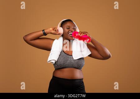 Young Black Woman Wearing Headphones Drinking Water At Studio Stock Photo