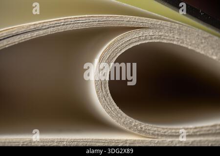 Extreme close up of white paper pages curving into a spiral with soft natural light and shadows Stock Photo
