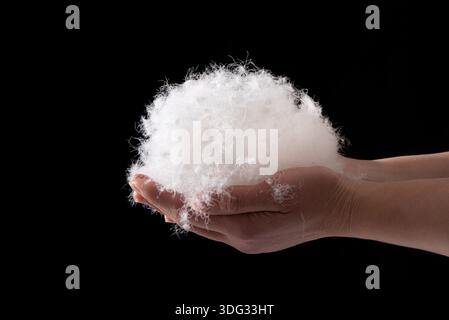 closeup of hand holding down feather on black background Stock Photo