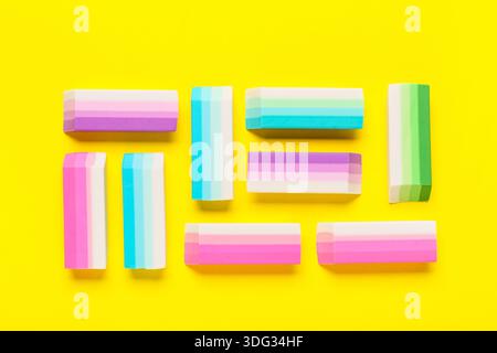 Many colorful rubber erasers on yellow background Stock Photo