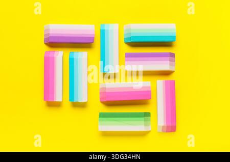 Many colorful rubber erasers on yellow background Stock Photo