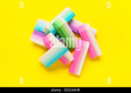 Many colorful rubber erasers on yellow background Stock Photo