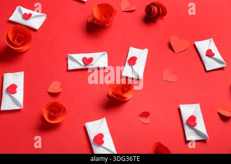 Envelopes with paper flowers and hearts on red background. Valentine's Day celebration Stock Photo