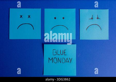 Symmetrical composition featuring three sticky notes showing sad faces above a central note with Blue Monday text on a blue background. Stock Photo