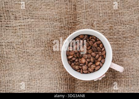 Close up of coffee beans in a cup. Coffee cup on textile background Stock Photo