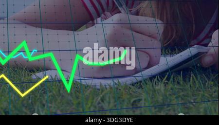 Writing woman striped shirt lying on grass, using pen on spiral-notebook, neon line graphs and grid Stock Photo