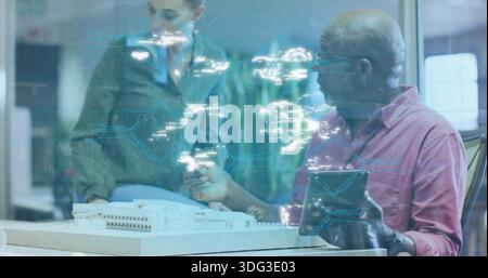Studying two in olive coat red-shirt in office, examining model and tablet with blue-circuit glass Stock Photo