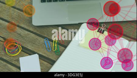 Showing open notebook with yellow note clipped by clip sitting at desk, laptop and pink or red overl Stock Photo