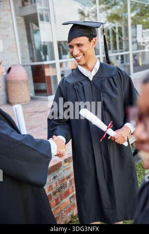 Happy man, student and graduation with handshake for thank you, achievement or milestone on campus. Male person, graduate or shaking hands with smile Stock Photo