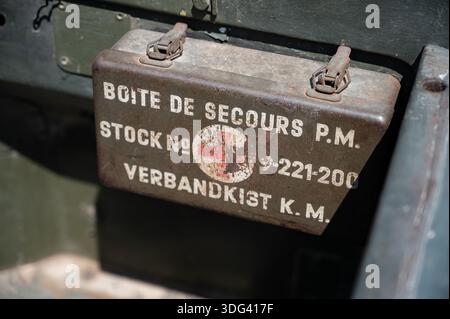 Close-up of a vintage metallic first aid kit inside a restored Minerva Motors military vehicle dashboard, featuring original markings and weathered re Stock Photo