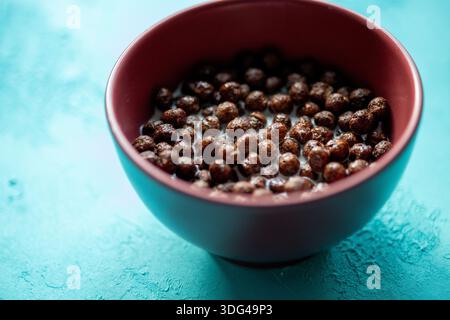 Close-up of crunchy chocolate corn flakes cereal with fresh white milk in a bowl Stock Photo