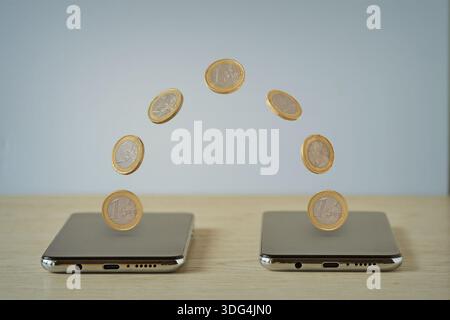 Coins moving from one smartphone to an other - Concept of digital money transaction Stock Photo
