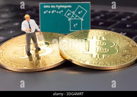 Miniature figurine depicting a businessman standing on golden Bitcoin coins in front of a board with a mathematical diagram. Stock Photo