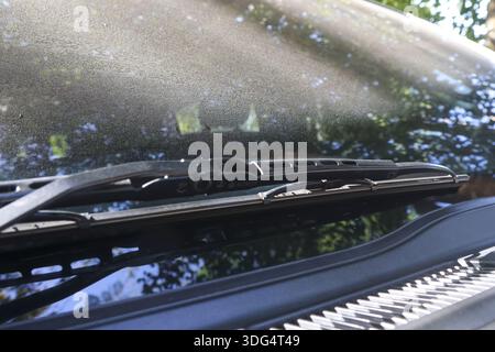 Dirty car windshield wiper covered in thick dust and grime needs cleaning maintenance. Close up detail of messy vehicle glass shows neglect and lack o Stock Photo