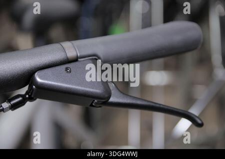 Close-up of a brake lever on an urban electric bicycle with a black ergonomic grip and brake mechanism housing. Control and safety details of a modern Stock Photo