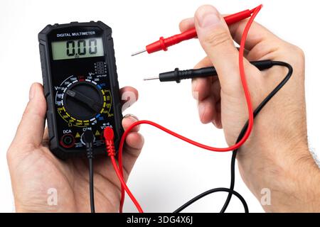 Cropped image of male repairman checking fridge with digital multimeter at home. Stock Photo