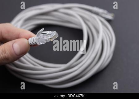 RJ-45 crimped red ethernet connector, unshielded twisted pair UTP internet cable end in hand, macro, detail, closeup. Individual cables visible. Cable Stock Photo