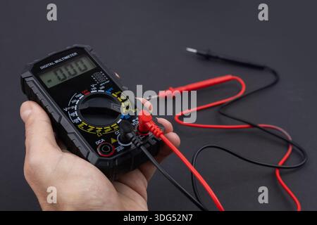 Cropped image of male repairman checking fridge with digital multimeter at home. Stock Photo