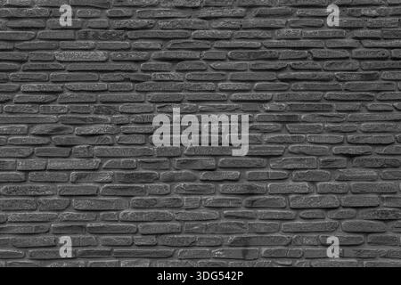 The black wall is made of uneven black gloomy stones. Abstract dramatic background. Stock Photo