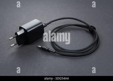 Black smartphone charger on dark background. Charger and USB cable type C on dark background. Stock Photo