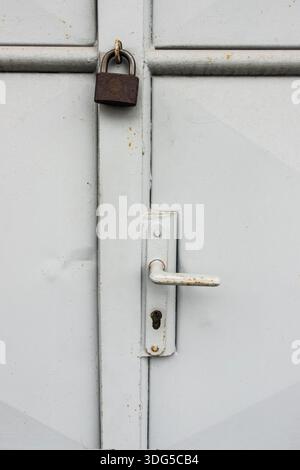 White metal door secured with a padlock, symbolizing security, privacy, and restricted access Stock Photo