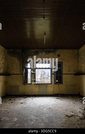 A deserted room with signs of severe neglect, open to the outside through broken windows, symbolizing time’s relentless erosion. Stock Photo