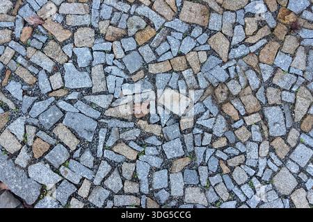 Patterned cobblestone pavement with mixed stone tones, photographed from above as a textured urban ground surface Stock Photo