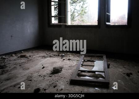 a broken window frame on the dusty floor and light pouring in from the outside. Stock Photo