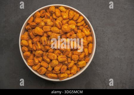 Close up shot of Roasted corn nuts with sauce in bowl, Corn nuts with bbq. Roasted corn snack close up food background. Top view with flat lay. Stock Photo