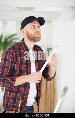 male electrician with clipboard repairing kitchen extractor Stock Photo