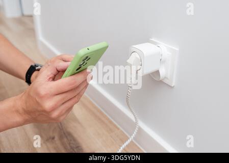 Using Wi-fi smart socket on the wall in a smart home, controlling electricity consumption Stock Photo