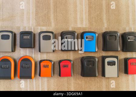 Wall mounted key lockboxes in various colors and designs on wooden surface Stock Photo