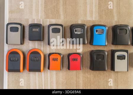 Wall mounted key lockboxes in various colors and designs on wooden surface Stock Photo