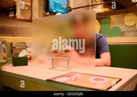 Blurred person in a booth behind a partition in a restaurant playing on a smartphone. Hongkong, China Stock Photo