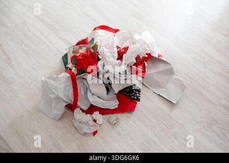 Messy pile of crumpled gift wrapping paper on wooden floor, recycling services, waste disposal, post-holiday sales. Stock Photo