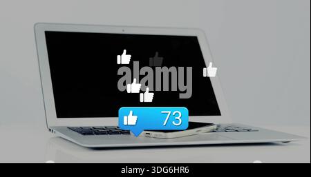 Displaying laptop and phone on glossy white table, showing like icons and blue 73 bubble Stock Photo