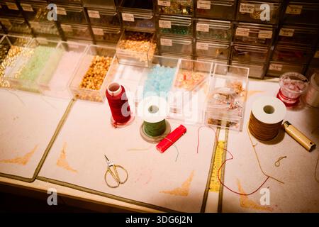 Craft workspace with colorful threads, beads, scissors, and organized storage boxes on a table. Shanghai, China Stock Photo