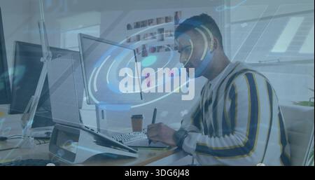 Working developer in striped sweater at desk inspecting AR overlay on laptop, monitors, copy space Stock Photo