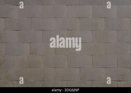 Wall surface covered with rectangular gray-brown tiles arranged in a staggered pattern. Tile shades vary slightly, with visible moisture marks and sig Stock Photo