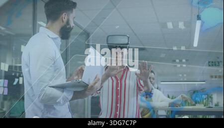 Reaching woman in striped shirt using VR headset interacting with virtual UI at office, with laptop Stock Photo
