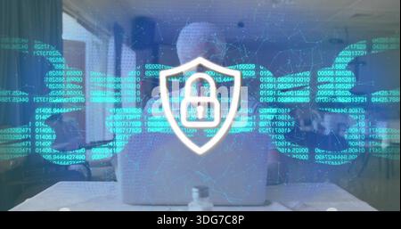Typing senior man wearing shirt at hotel table with bottle, showing padlock overlay on laptop Stock Photo
