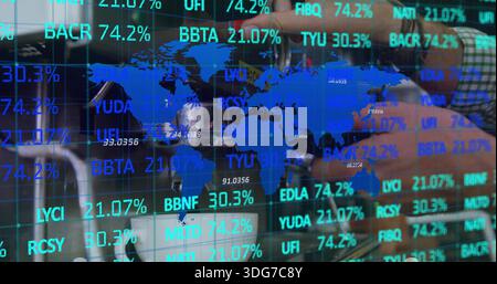 Displaying blue world map and tickers on glass in office, forearm in green plaid shirt reaching Stock Photo
