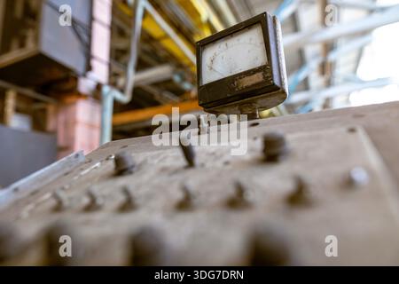 Close up of retro analog gauge and toggle switches on vintage factory control panel. Industrial engineering and power monitoring equipment. Traditiona Stock Photo