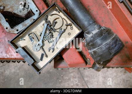 Small metal tools and fasteners in organizer box on industrial workbench. Maintenance and repair process with hand tools and hardware parts. Engineeri Stock Photo