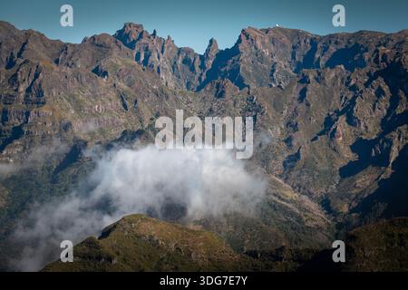 Rugged cliffs and sharp peaks of Madeira’s central mountain range rise above a floating layer of clouds, seen from Bica do Cana viewpoint on Madeira Stock Photo