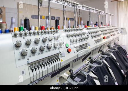 Automated multi head embroidery machine in textile factory. Professional branding process of restaurant workwear and chef aprons using industrial high Stock Photo