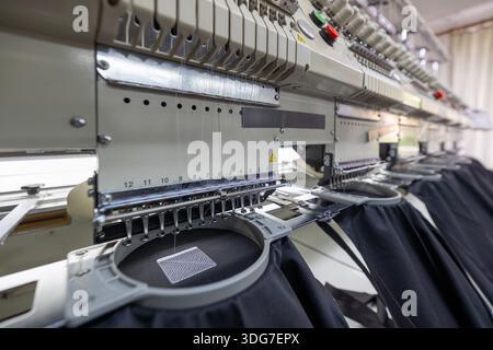 Close up of multi head embroidery machine stitching logo. Process of automated branding on restaurant staff uniforms using professional industrial equ Stock Photo
